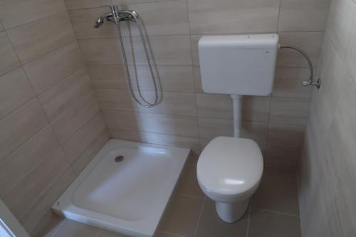 a small bathroom with a toilet and a shower at Robinson olive tree huts in Čara