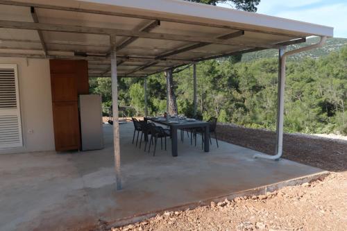 a patio with a table and chairs under a roof at Robinson olive tree huts in Čara