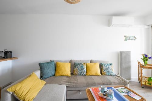 ein Wohnzimmer mit einem grauen Sofa und bunten Kissen in der Unterkunft Le Superbe Bahia / proche mer / clim / Terrasse / parking privé in La Grande-Motte