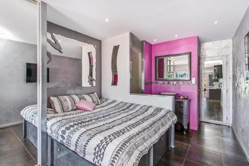 - une chambre avec un grand lit aux murs roses dans l'établissement Palmeraie beach Heliopolis Naturiste, au Cap d'Agde