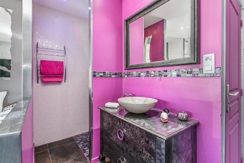 une salle de bain rose avec un lavabo et un miroir dans l'établissement Palmeraie beach Heliopolis Naturiste, au Cap d'Agde