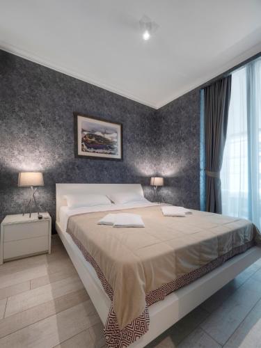 a bedroom with a large bed and a wall at Royal Montesun Apartments in Budva
