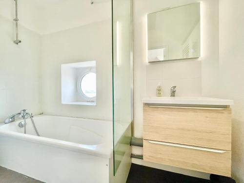 La salle de bains est pourvue d'une baignoire, d'un lavabo et d'un miroir. dans l'établissement LE BALI - Proche de la gare - Appartement Deluxe - Tout confort - Lumineux - Internet haut débit Fibre - 1 chambre - NETFLIX, à Lorient