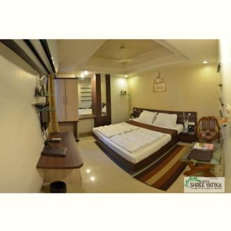 a bedroom with a large bed and a table at Hotel Shree Vatika in Bhopal