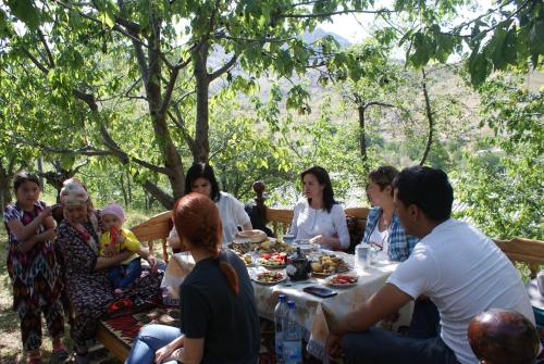 a group of people sitting around a table eating at Spring Family Guest House in Tersak