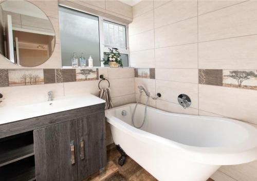 a bathroom with a tub and a sink and a mirror at 82 De Bakke Terrace in Mossel Bay