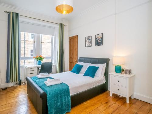 a bedroom with a bed and a chair and a window at Pass the Keys Superb 1 Bed Flat in Traditional Victorian Building in Edinburgh
