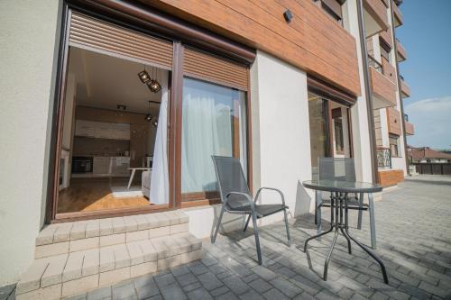 a patio with a table and chairs in front of a window at Aria Club Wellness&Spa Zlatibor in Zlatibor