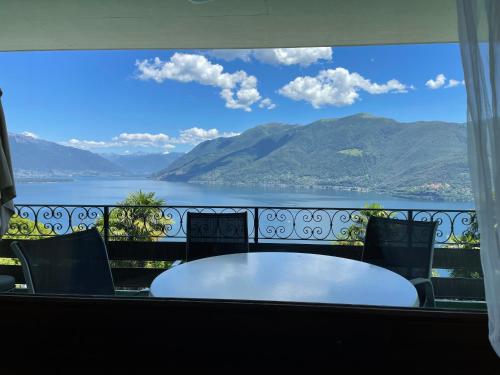 einen Tisch und Stühle auf einem Balkon mit Blick auf das Wasser in der Unterkunft Brissago: Casa Collinetta H in Brissago