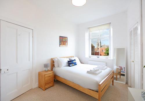 a white bedroom with a bed and a window at Seagulls in North Berwick