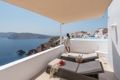 a woman standing on a balcony looking out at the ocean at Aspaki by Art Maisons in Oia