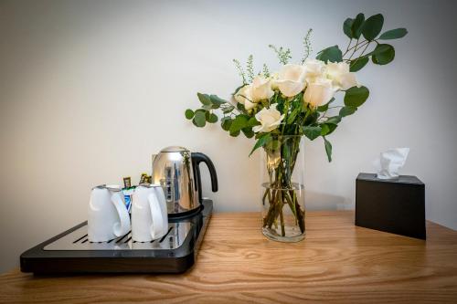 a vase of roses and a tea kettle and a vase of flowers at Loch Ness Inn in Drumnadrochit