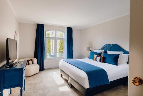 1 dormitorio con 1 cama extragrande y cortinas azules en Hostellerie Cèdre & Spa Beaune, en Beaune