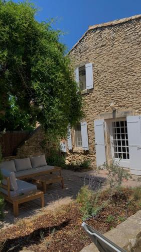 - un bâtiment en pierre avec un canapé et des tables en face dans l'établissement La Maison de la Forge, à Gordes