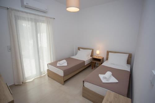 deux lits dans une chambre avec une fenêtre dans l'établissement George‘s Place Kastrosikia, à Kastrosikia