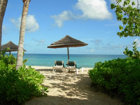 two chairs and an umbrella on the beach at Northshore Seaside Suites in Saint Johnʼs