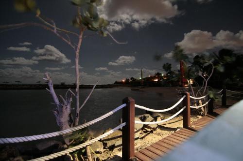 a fence and a tree next to a body of water at Northshore Seaside Suites in Saint Johnʼs