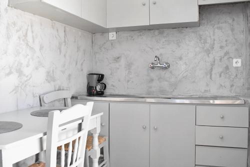 a white kitchen with a sink and white cabinets at Giagia Annousio in Dhriopís