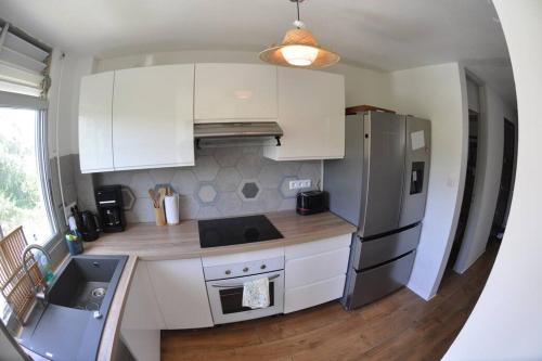 a kitchen with white cabinets and a stainless steel refrigerator at Paradise Duplex avec piscine et accés Plage in Le Gosier