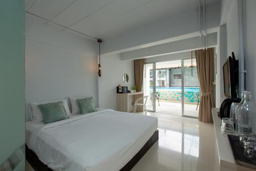 1 dormitorio con cama, TV y piscina en The Nest Resort Patong, en Patong Beach