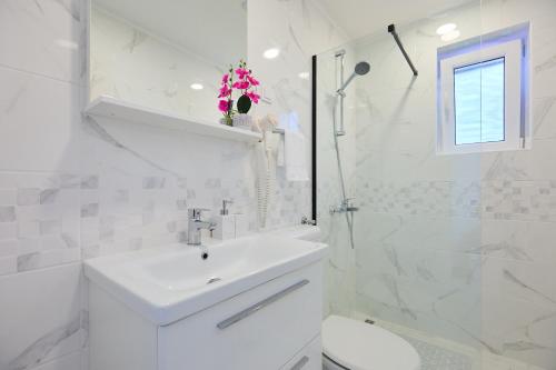 a white bathroom with a sink and a toilet at Apartment Manilu in Dubrovnik