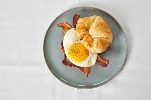 a plate with an egg and bacon and a croissant at Virgin Hotels New Orleans in New Orleans