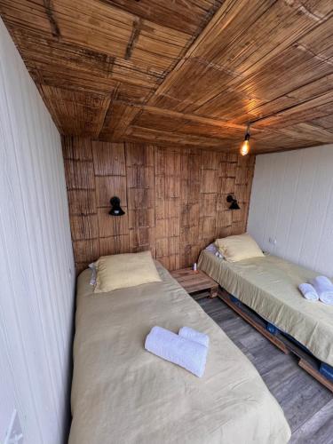 two beds in a room with wooden ceilings at El Filito in San JosÃ©