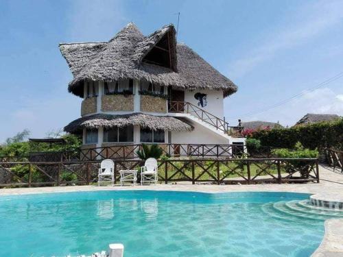 a villa with a pool in front of a house at Miky House in Watamu