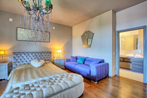 een slaapkamer met een blauw bed en een bank bij Casa White by PosarelliVillas in Castiglion Fiorentino