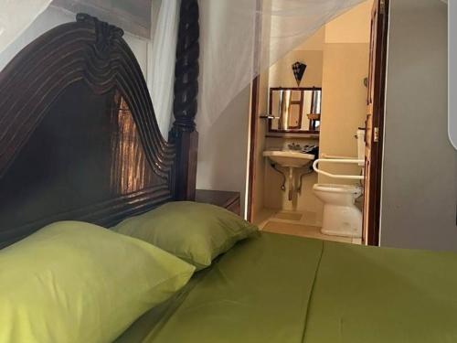 um quarto com uma cama com uma cabeceira de madeira em Miky House em Watamu