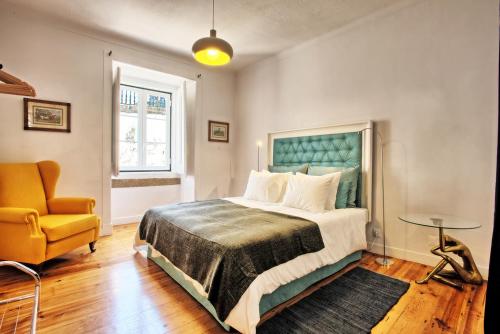 a bedroom with a large bed and a chair at Portas da Sé Apartments in Lisbon