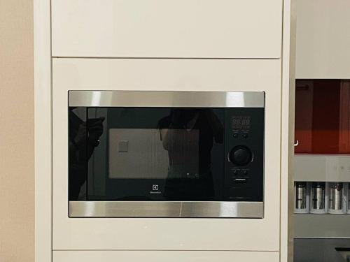 a microwave in a white cabinet with its door open at Arcoris Mont Kiara 1 to 5 pax Designer Netflix Chill Balcony in Kuala Lumpur