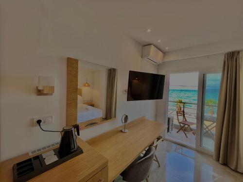 Habitación con escritorio, cama y TV. en Hotel Pefkohori Beach en Pefkohori