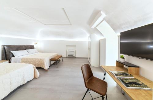 1 dormitorio con 2 camas, escritorio y TV en Casa Neval Lacco Ameno, en Isquia