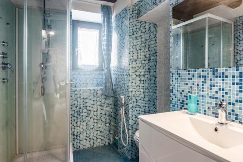 baño con lavabo y ducha con azulejos azules en Nearby 5Terre Authentic Apartment, en Carrodano Inferiore