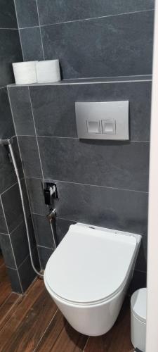 a white toilet in a bathroom with black tiles at Leśniczówka Kalina in Wetlina