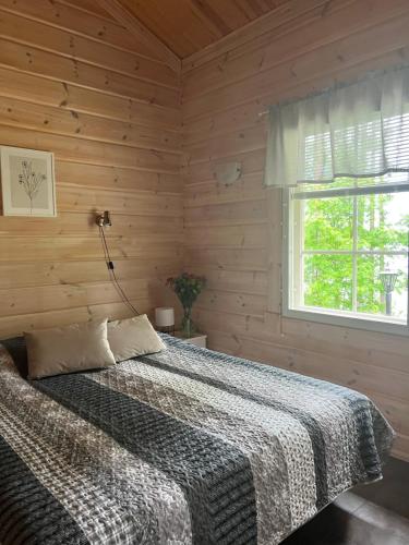 a bed in a wooden room with a window at Holiday Home Amero purnu 2 in Kolinkylä