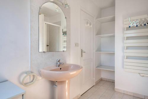 une salle de bain blanche avec un lavabo et un miroir dans l'établissement Maison pour 8 - Piscine - 950m de la mer, à Saint-Gildas-de-Rhuys