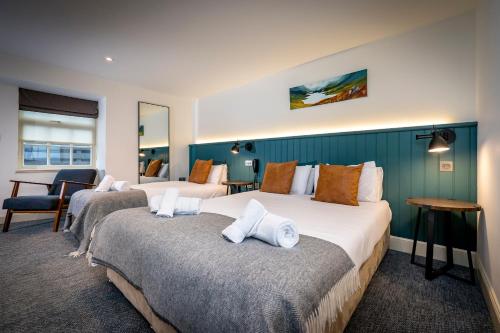 a hotel room with two beds and a chair at Loch Ness Inn in Drumnadrochit