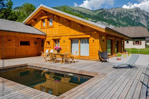 a log cabin with a wooden deck and a pool at Chalet aux 3 biches in Mieussy