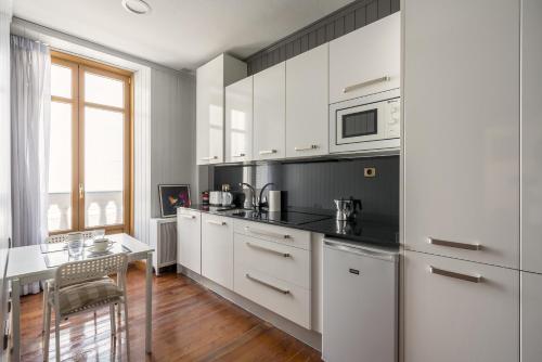 a white kitchen with white cabinets and a table at Ayala apartment by People Rentals in Bilbao