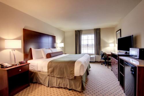 a hotel room with a large bed and a desk at Cobblestone Inn & Suites - Linton in Linton
