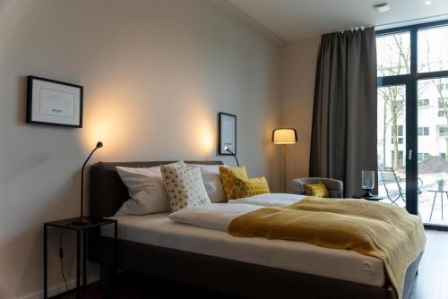 a bedroom with a bed with a yellow blanket on it at Arbio I Duxen Apartments Hagenbeck Zoo in Hamburg