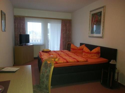 Habitación de hotel con cama con almohadas de color naranja en Zur Linde, en Ostrau