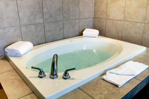 a bath tub with a sink in a bathroom at Cobblestone Inn & Suites - Linton in Linton