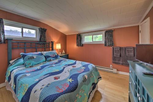 a bedroom with a bed with a blue comforter and two windows at Pet-Friendly Togus Pond Home Kayak and Canoe! in Augusta
