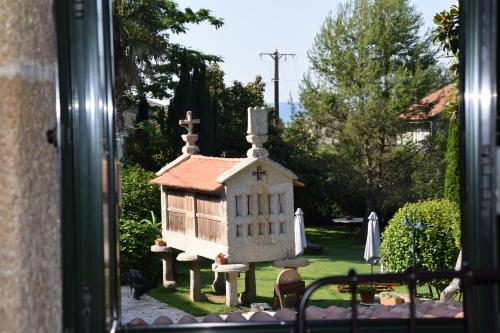 a window view of a small house in a yard at Casa Videira - Hotel rural cerca del mar in Bueu