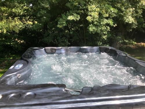 un bain à remous en métal avec de l'eau. dans l'établissement PAUSE NATURE SORBAIS Gite de groupe avec Piscine, Spas, Sauna avec 8 chambres et 8 salles de bain, grande cuisine et grande salle de vie, à Sorbais