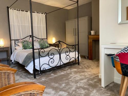 La Belle Demeure في Saint-Cybranet: غرفة نوم مع سرير مظلة سوداء مع ملاءات بيضاء