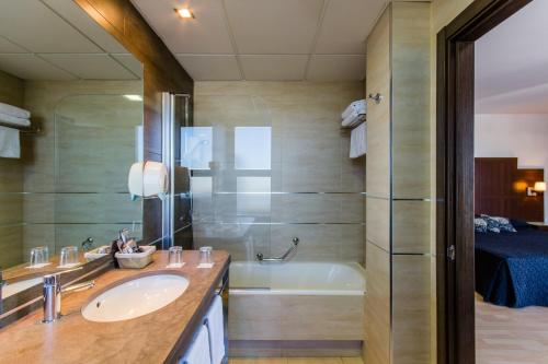ein Badezimmer mit einem Waschbecken und einer Badewanne in der Unterkunft YIT Conquista de Granada in Peligros